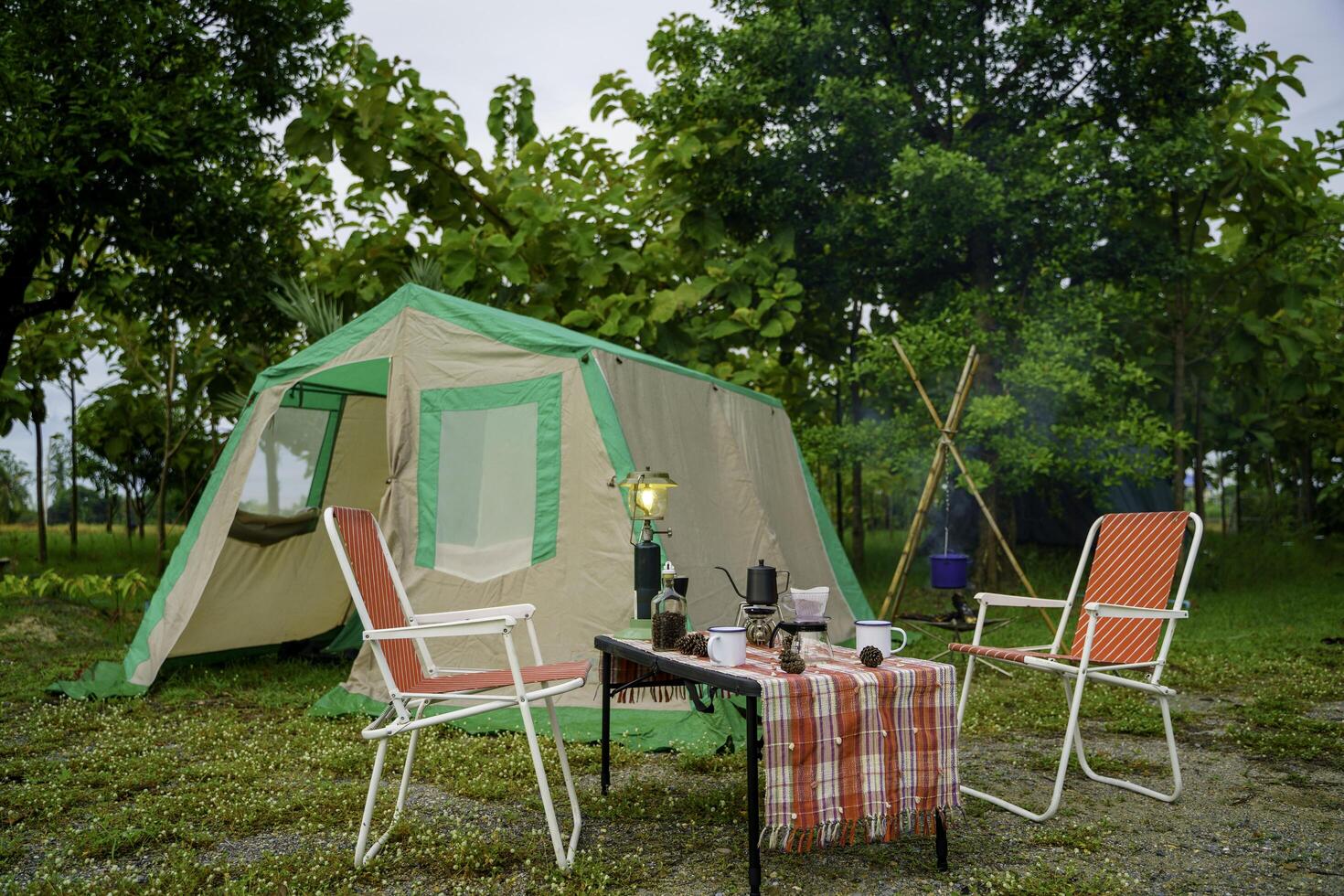 The vintage drip coffee set and baguette are in selective focus on a table in front of a camping tent in the forest in the morning. photo