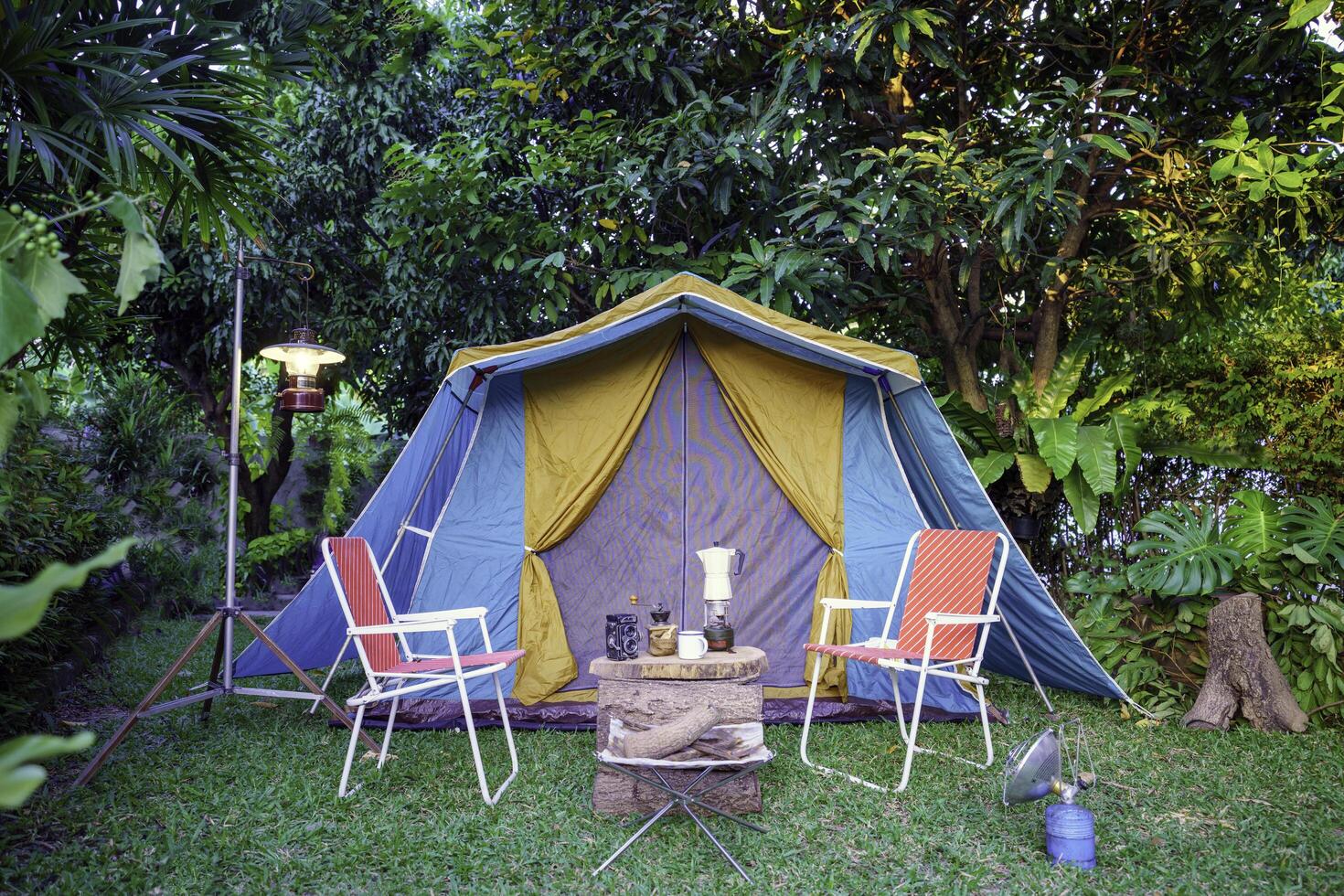 Camping tents, vintage cabin tents, antique oil lamps, retro chairs, and a group of camping tents with outdoor coffee-making facilities on wooden tables in a forest camping area in the forest photo