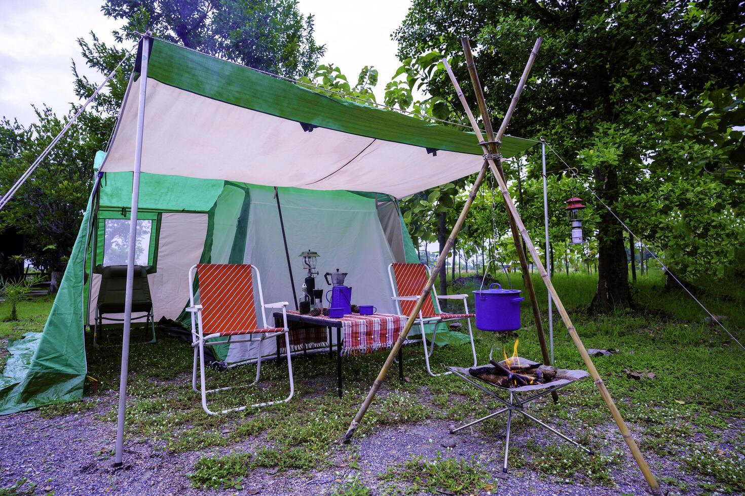 Camping tents at night, vintage cabin tents, Antique lanterns, retro chairs, and outdoor coffee-making facilities on wooden tables in a forest photo