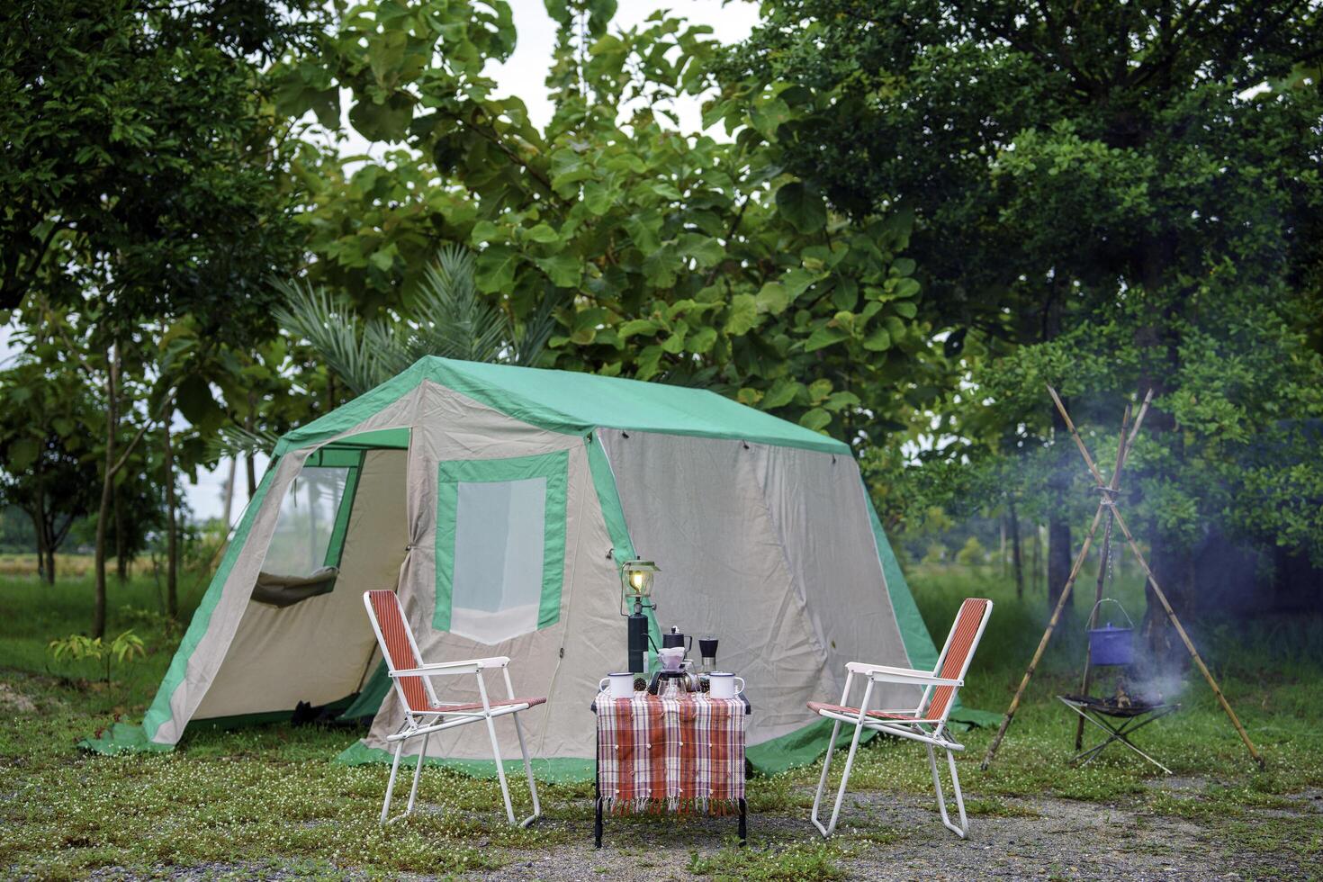 selective focus of vintage coffee set on the old wooden table In front of the retro cabin tent, retro chairs, Group of camping tents, and soft focus. photo