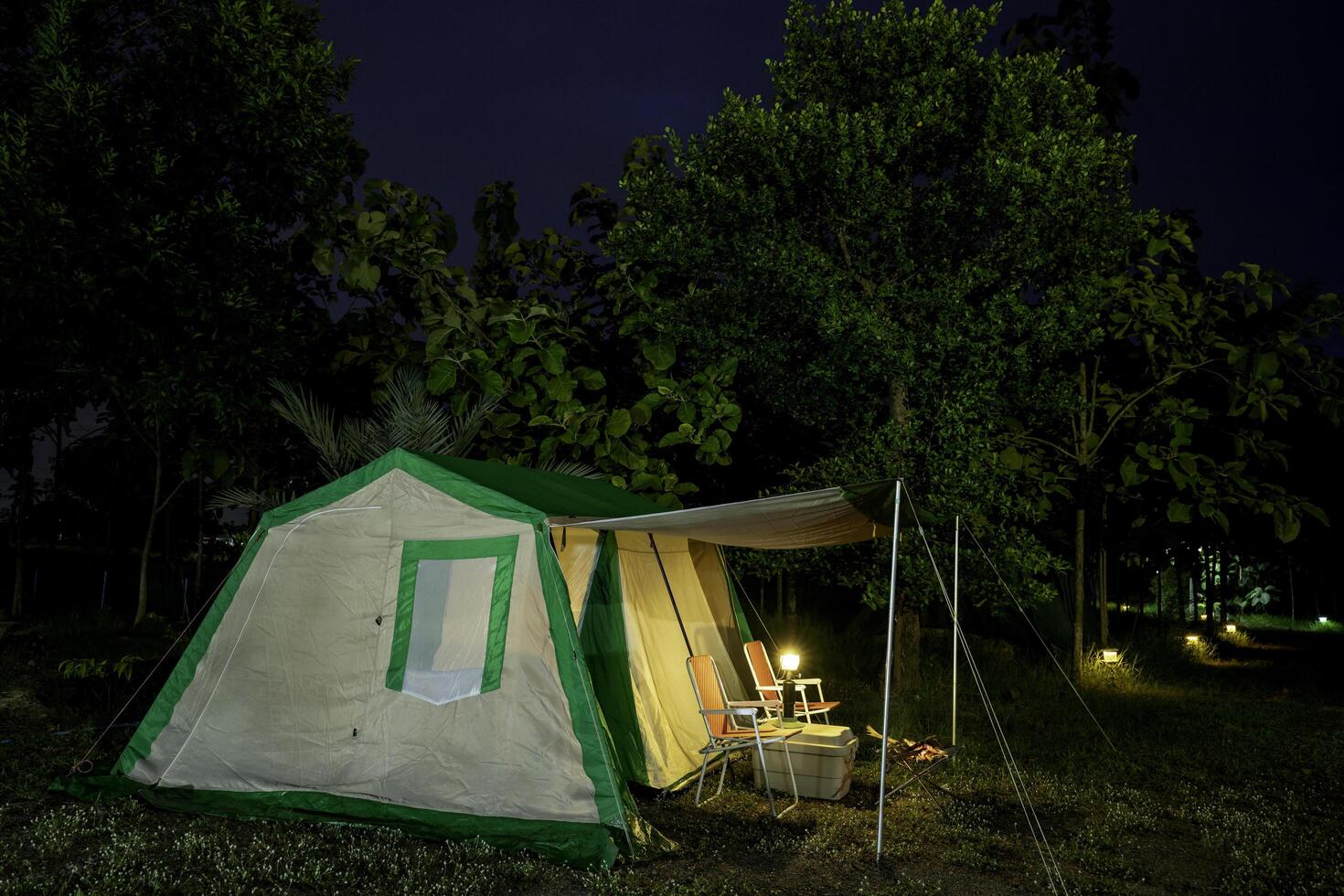 Camping tents at night, vintage cabin tents, Antique lanterns, retro chairs in the forest photo