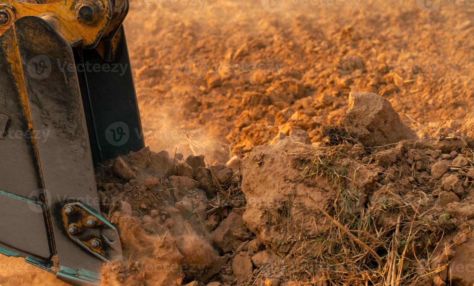 Metal bucket of backhoe digging soil. Excavator working at construction site. Earth moving machine. Excavation vehicle. Heavy machinery in action. Construction machinery and earth-moving equipment. photo