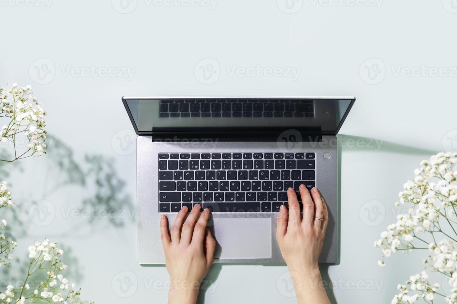 Overhead shot of womans hands working on laptop on blue background photo