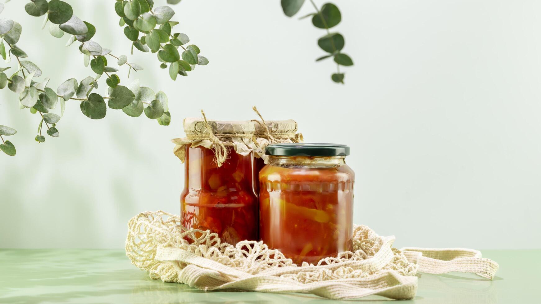Fermented vegetables in glass jars on textile bag on blue background photo