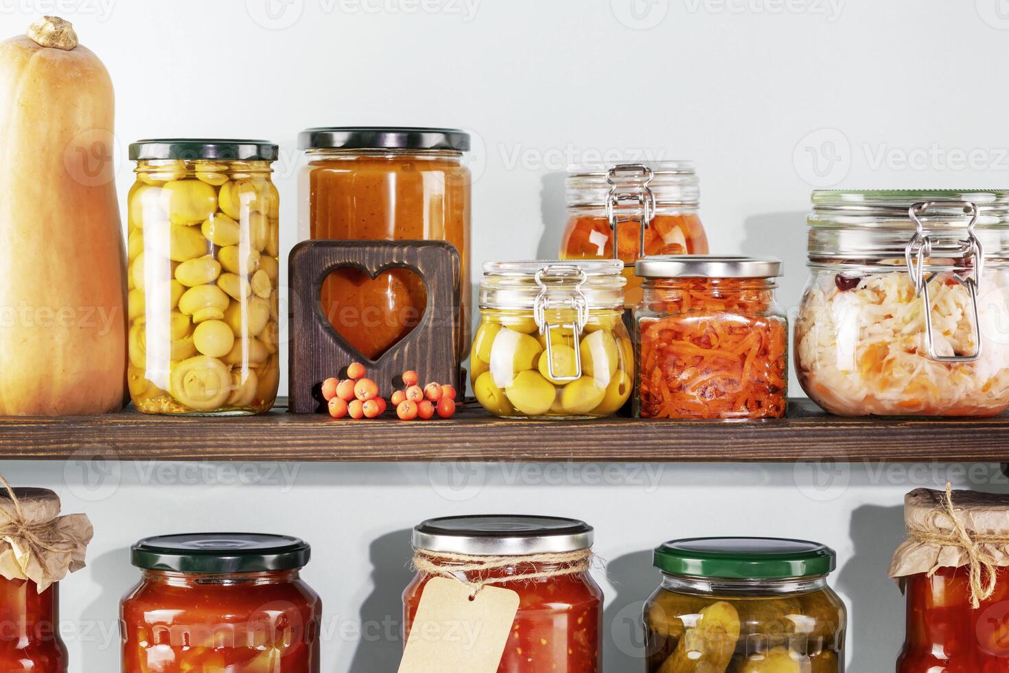 Fermented vegetables and mushrooms in glass jars placed in rows on wooden photo