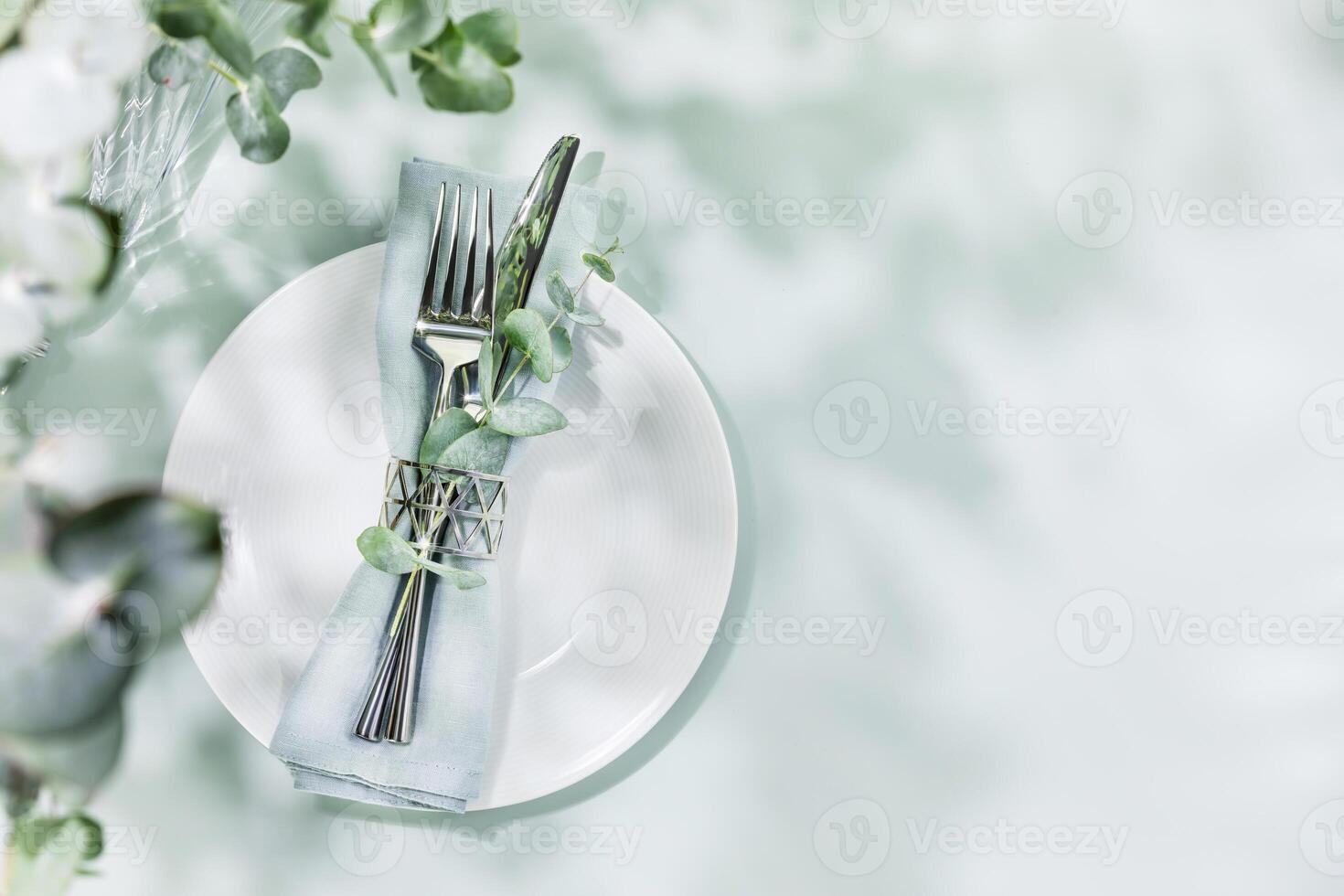 Table settings on blue background with eucalyptus leaves and copy space photo