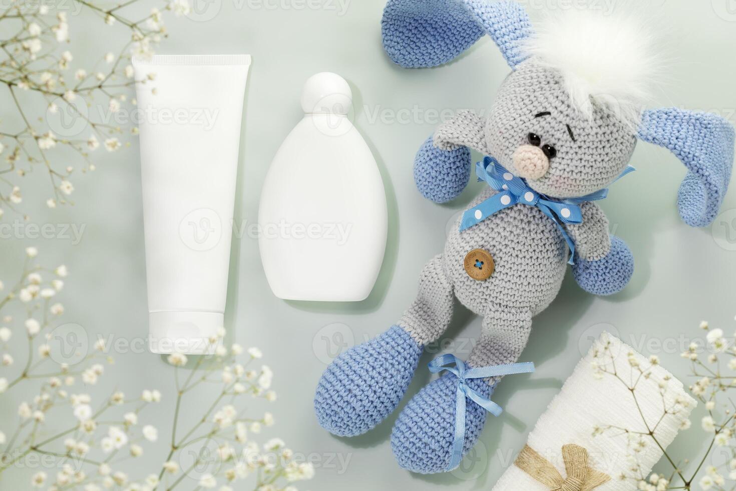 White bottles with child beauty products, towel and toy rabbit photo