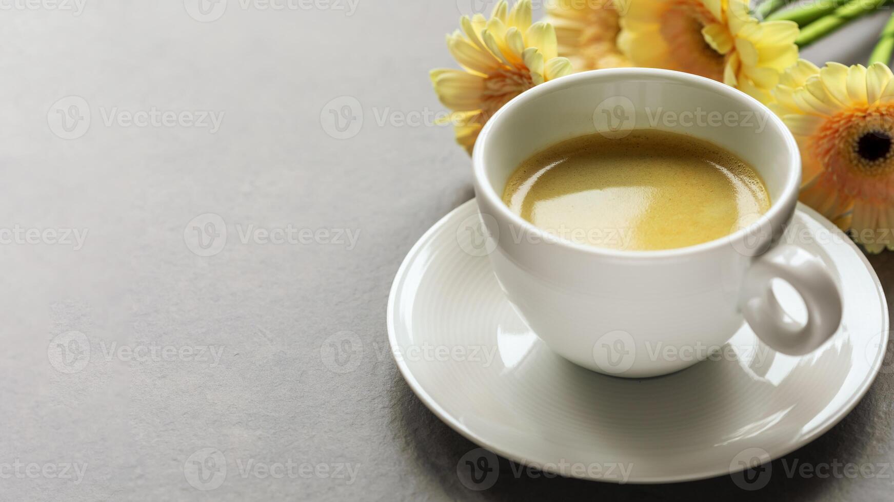 Cup of espresso with gerberas on grey marble background with copy space photo