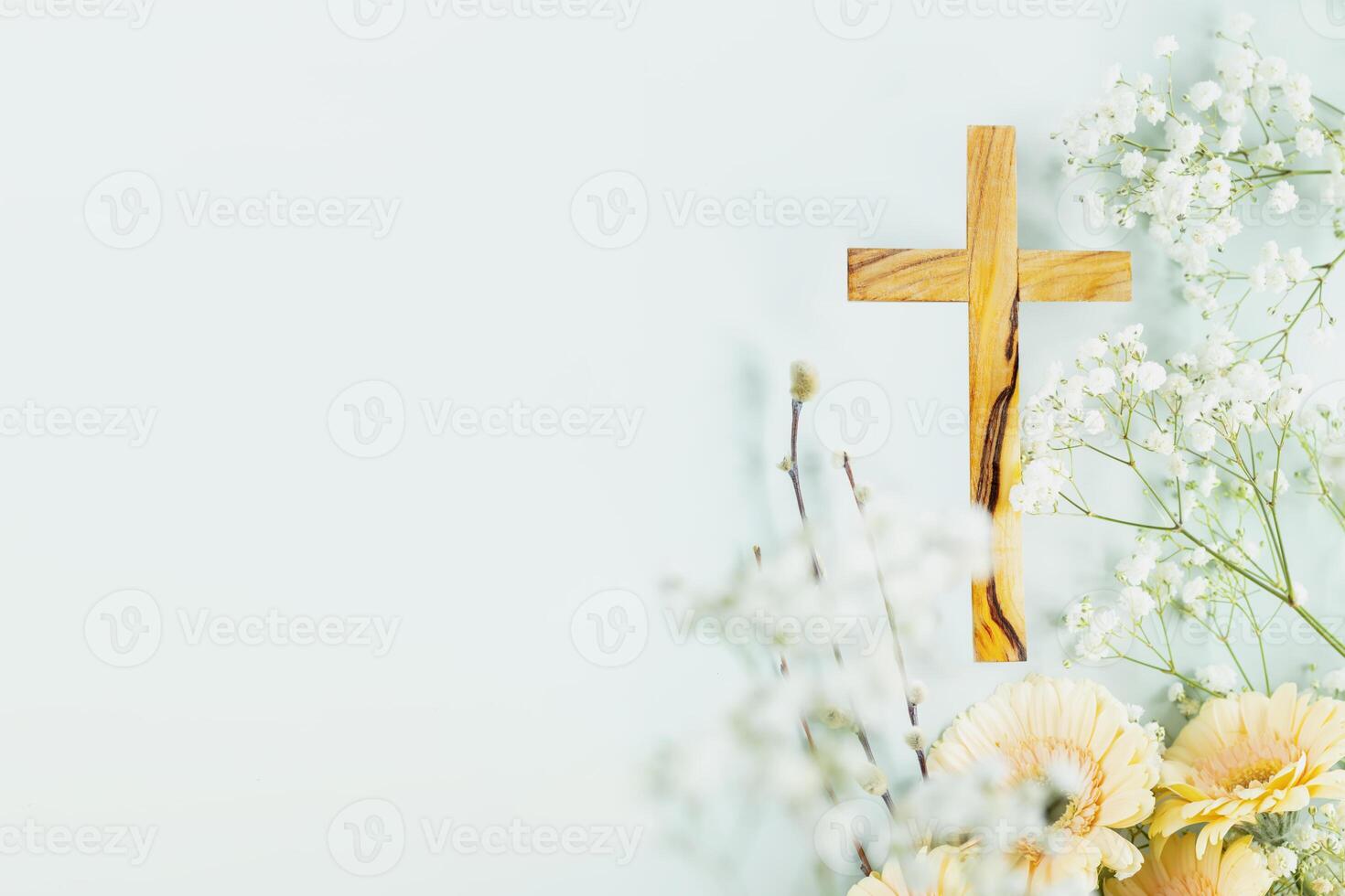 Wooden cross with spring flowers on blue background with copy space photo