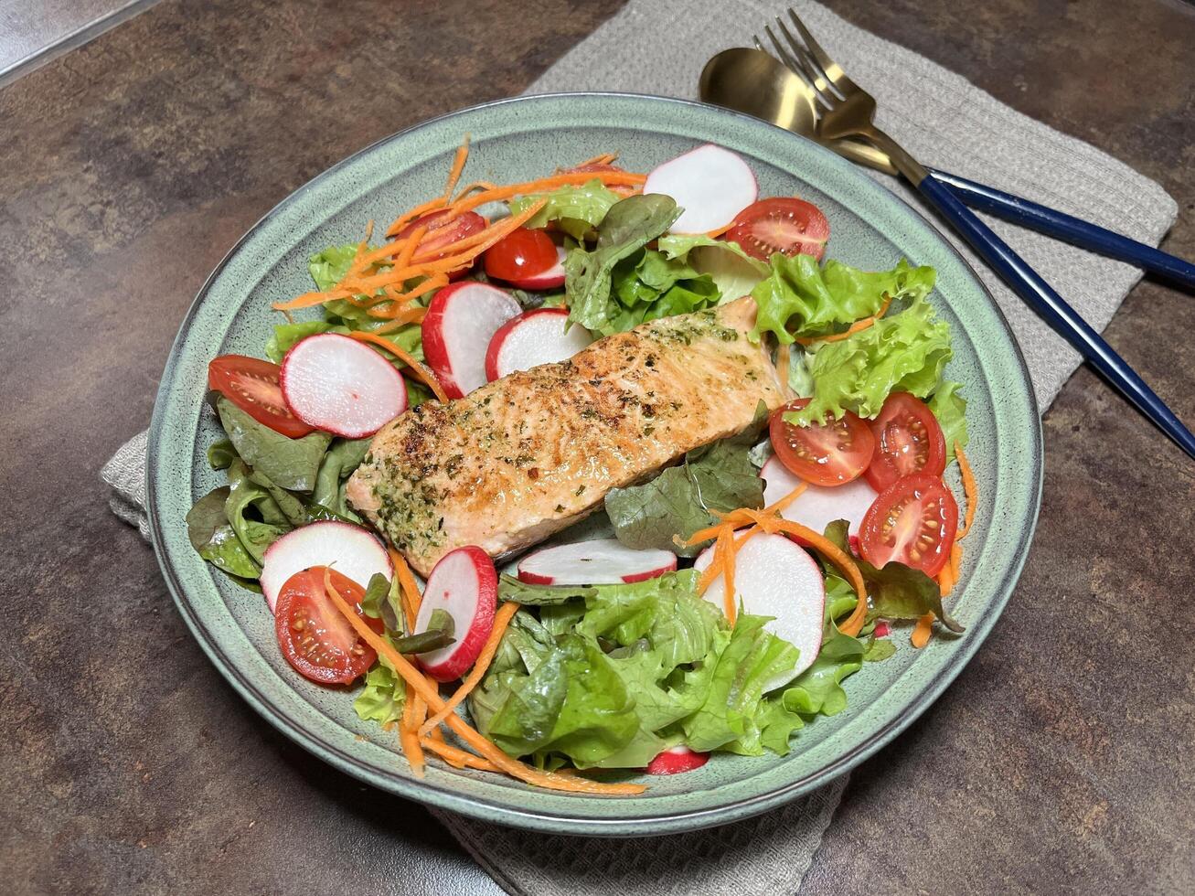 A perfectly cooked salmon fillet with a herb crust, served on a bed of fresh greens with cherry tomatoes, carrots and radishes photo