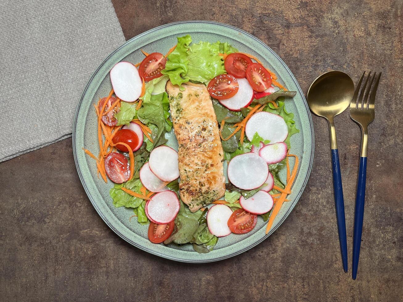 A perfectly cooked salmon fillet with a herb crust, served on a bed of fresh greens with cherry tomatoes and radishes photo