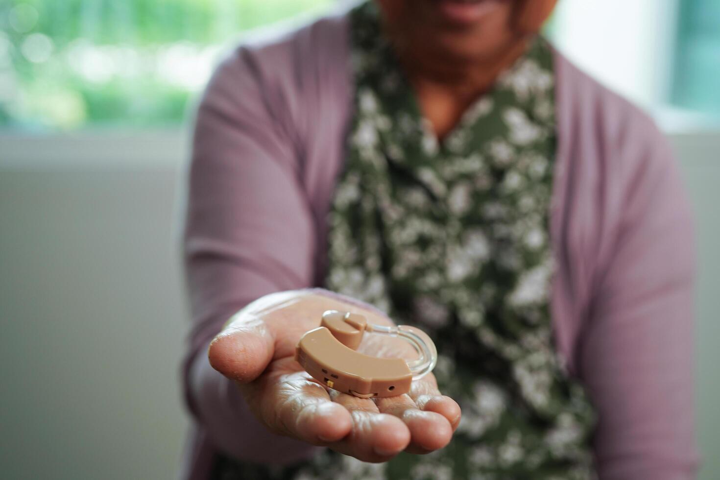 Asian senior woman patient using hearing aid in ear to reduce hearing loss problem. photo