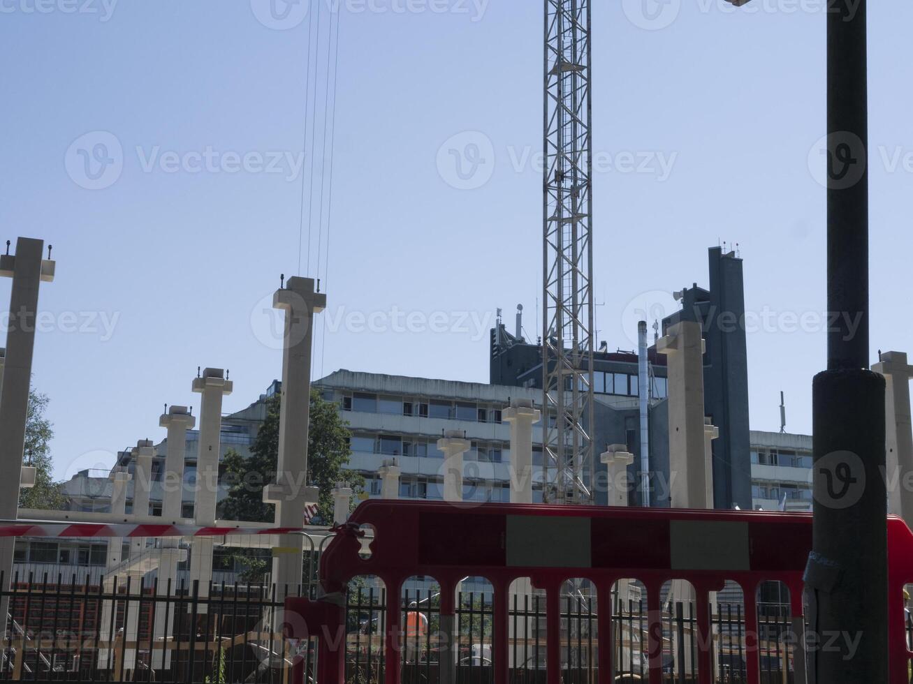 Crane in background working on a building under construction. Building framework visible as crane operate. Construction workers busy at the building site. Building development in progress. photo