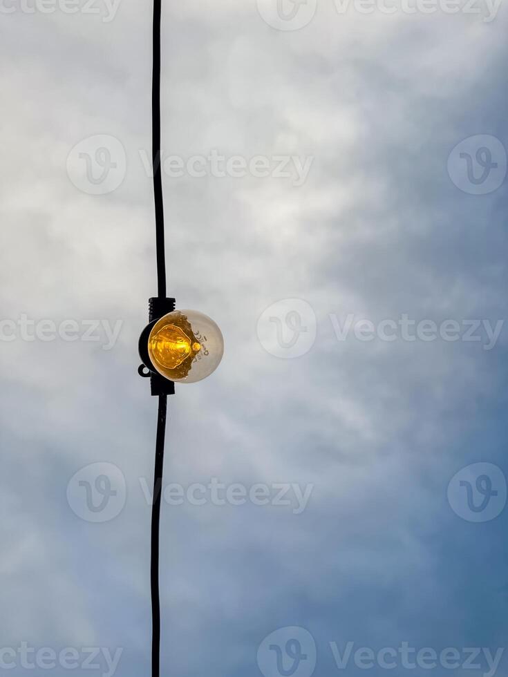 Small vintage glowing light bulb on black background. Electricity concept. High quality photo