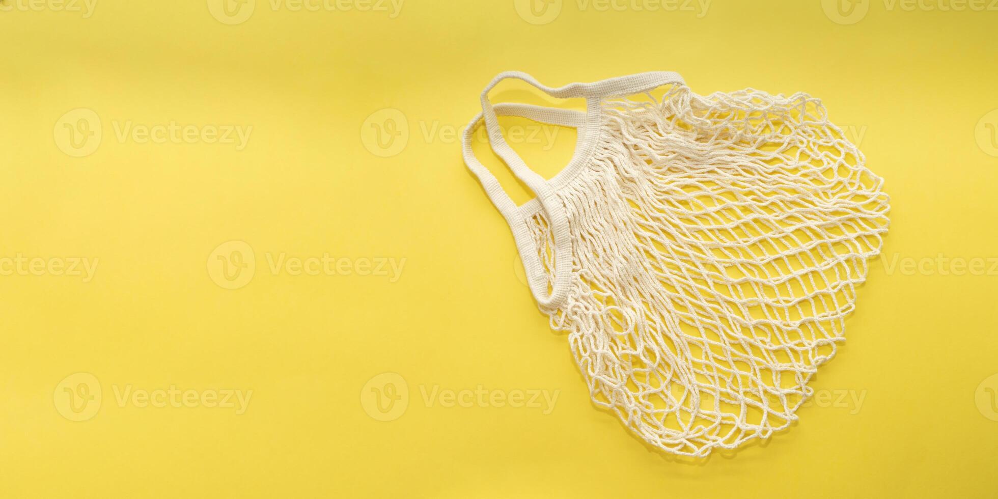 Reusable cotton shopping string bag on bright yellow background. Copy space. zero waste concept, no plastic. photo