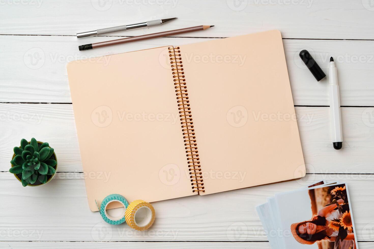 Creative workspace with open notebook, stationery, and decorative items on a wooden table photo