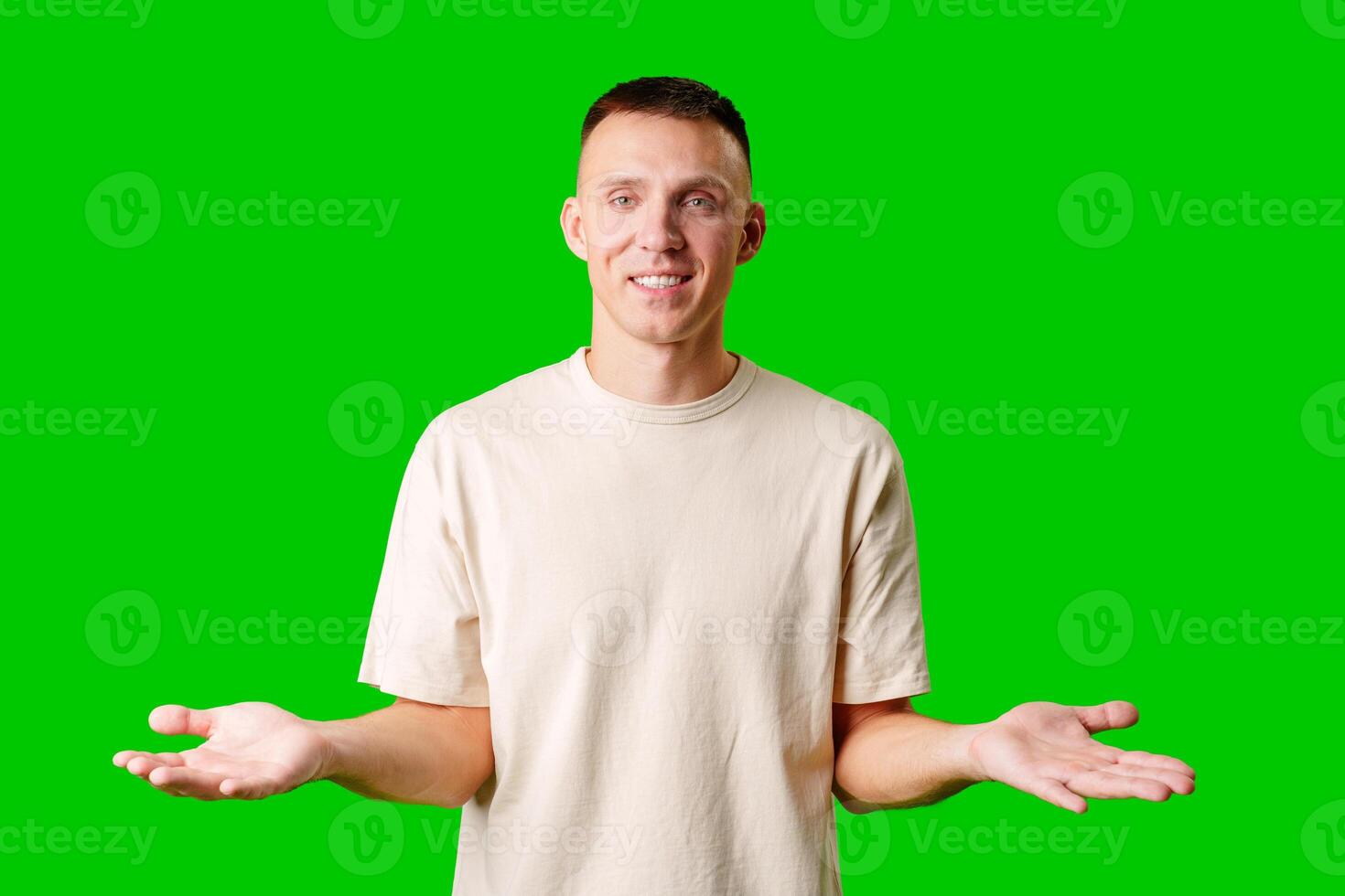 Young Man With Neutral Expression Shrugging His Shoulders Against Bright Green Background photo