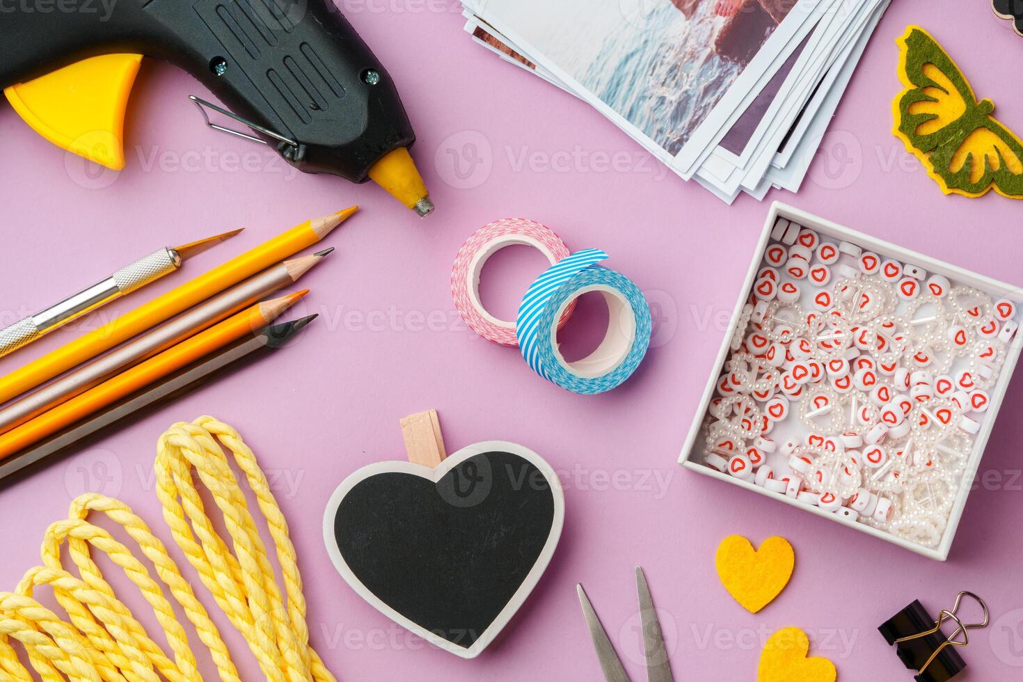 Crafting supplies arranged on a pink background, including glue gun, scissors, and decorative items for DIY projects photo