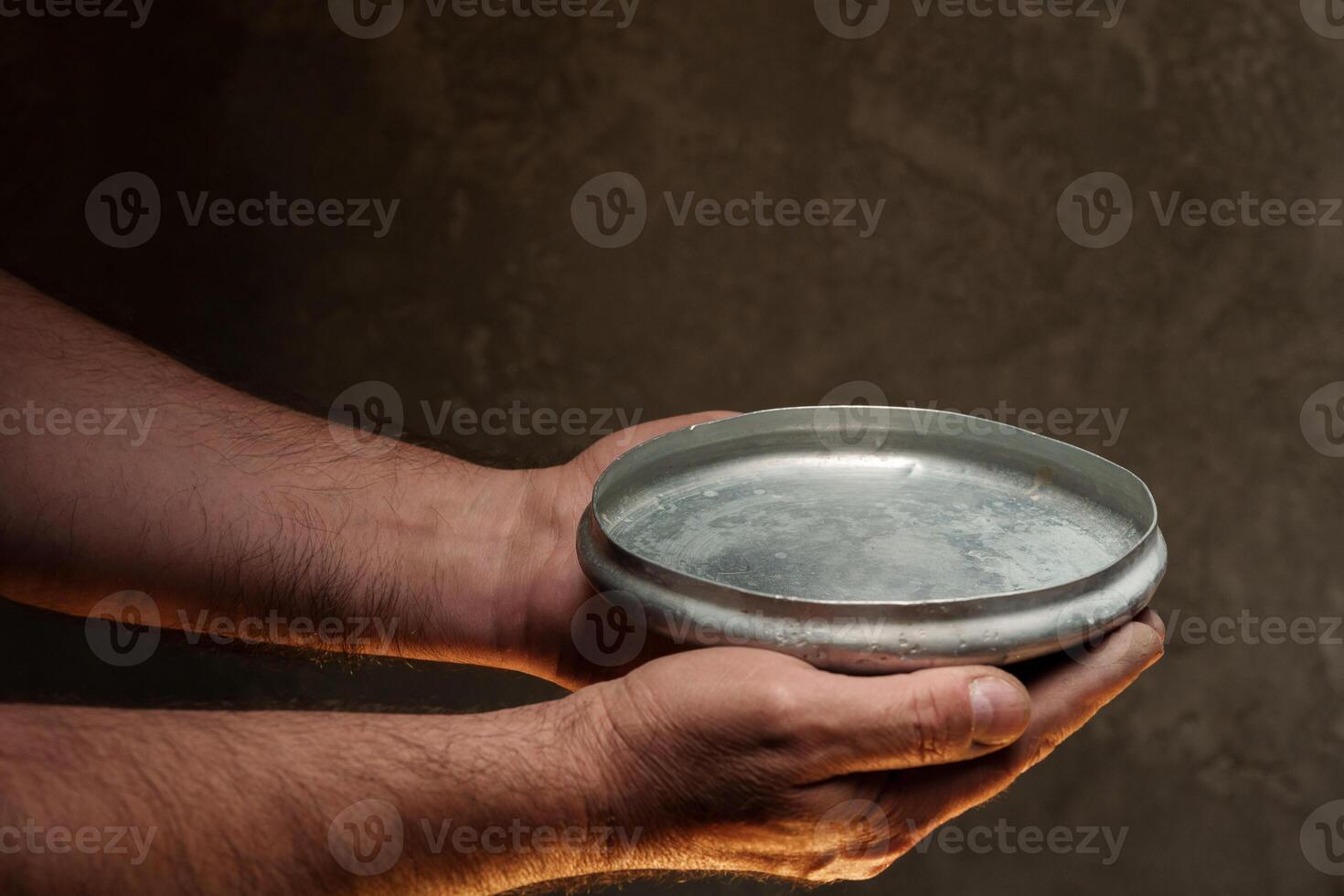 Male hands holding empty plate on dark background, lack of food, hunger concept. photo