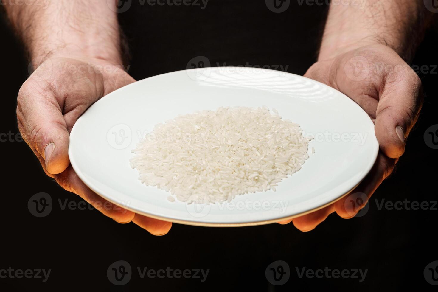 Hands holding a heap of dry rice grain on black background photo