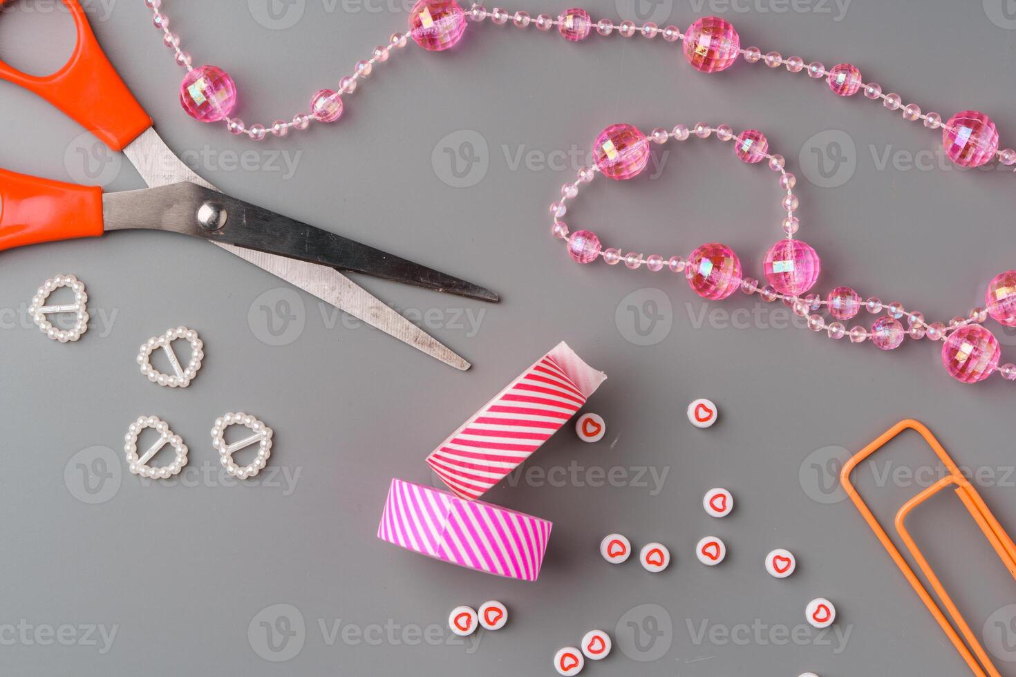 Crafting supplies arranged for a DIY project on a gray table with scissors, washi tape, and decorative items photo