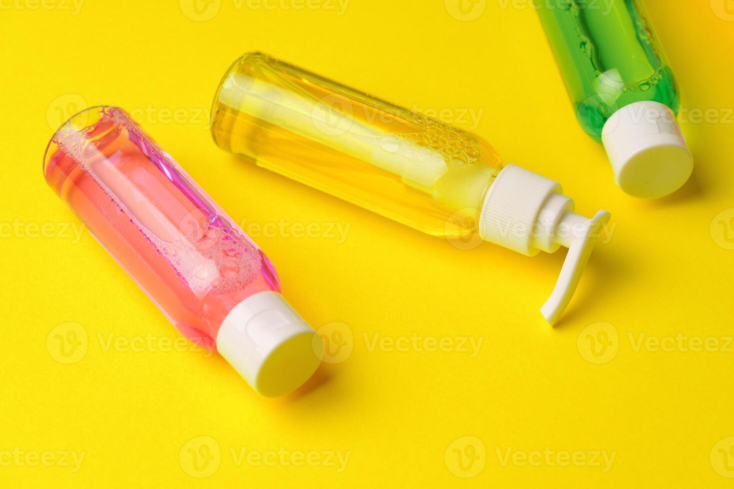 Colorful Bottles of Liquid Soap on Yellow Background photo