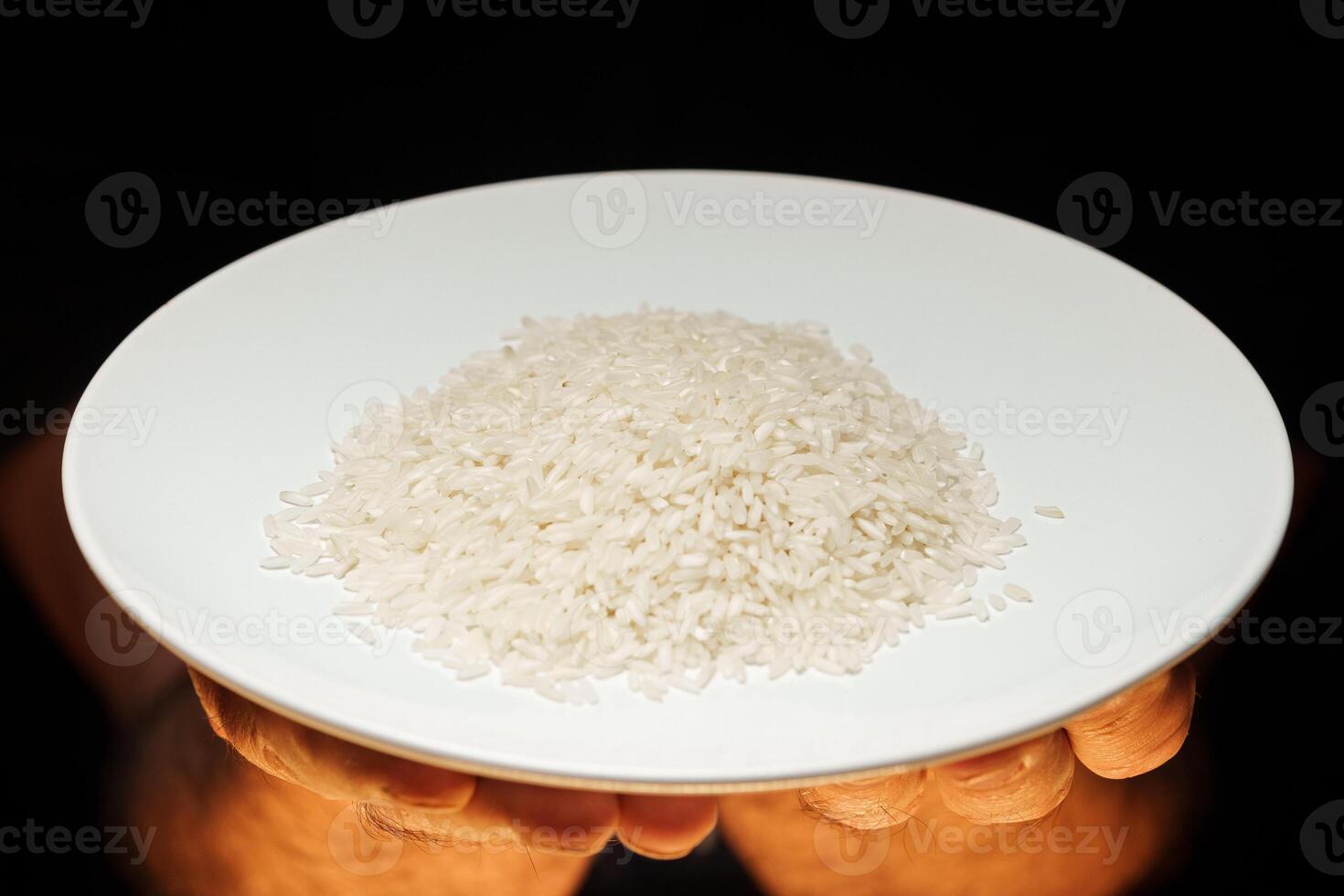 Hands holding a heap of dry rice grain on black background photo