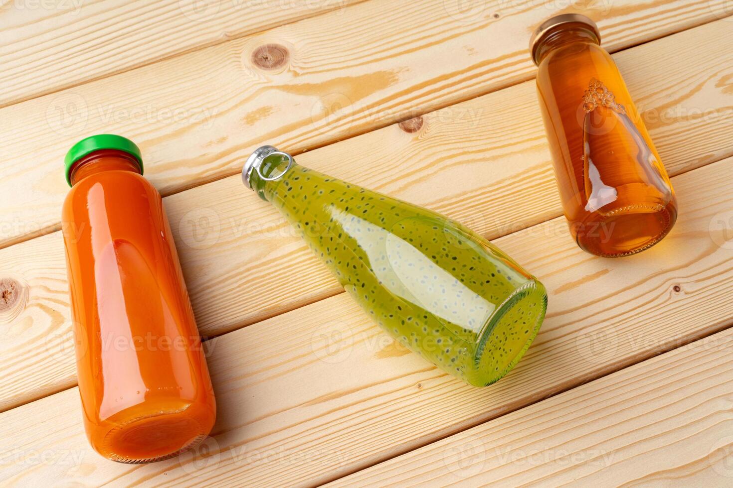 Different bottles of juice on wooden table photo