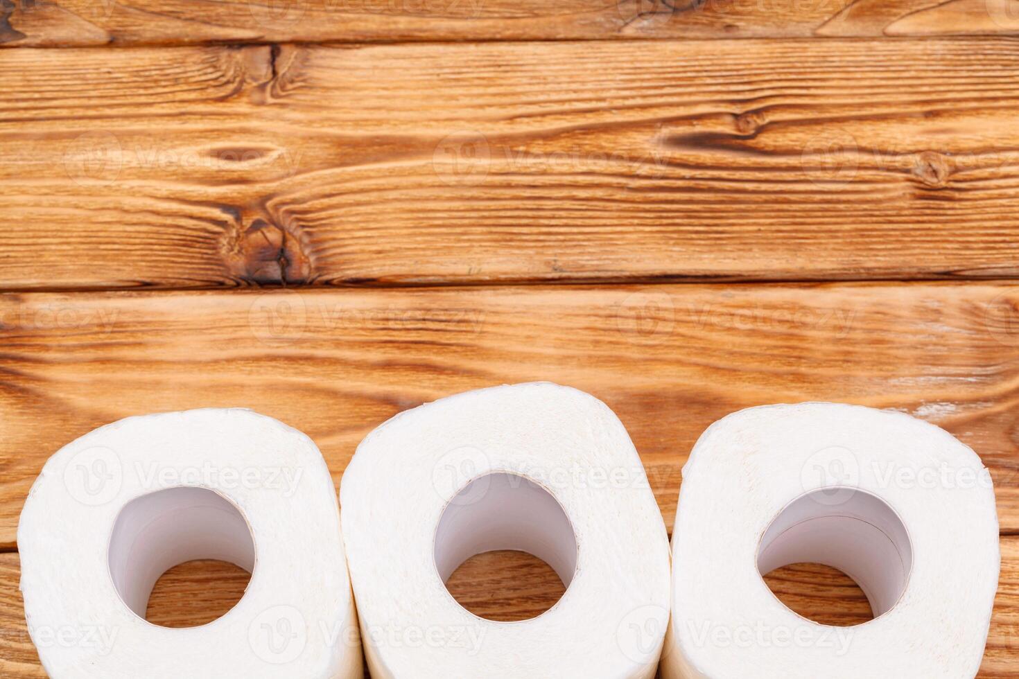 Toilet paper rolls on wooden background top view photo
