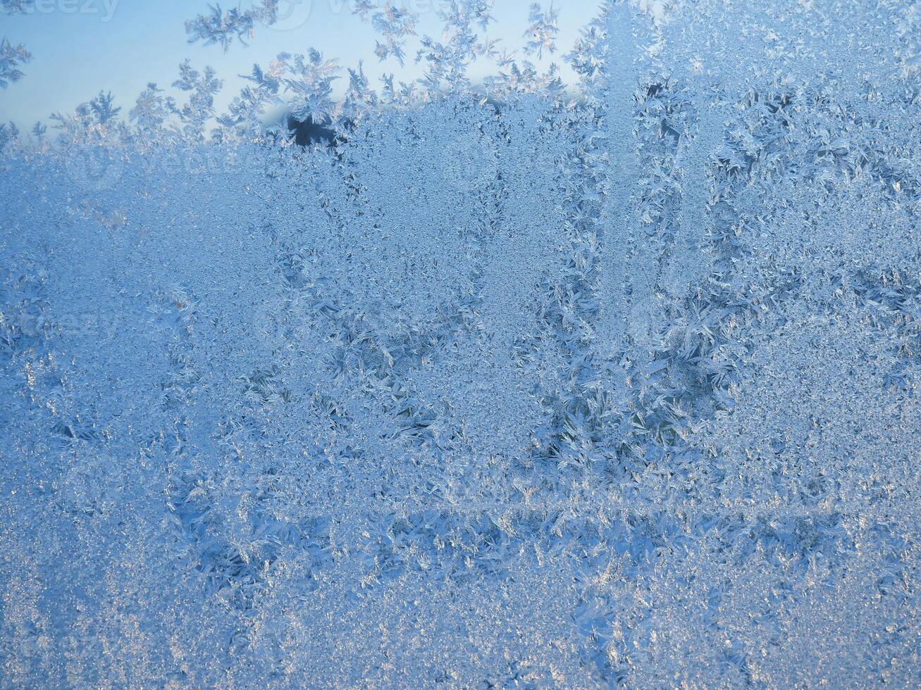Winter frost patterns on glass. Ice crystals or cold winter background.Beautiful natural frosty pattern on winter window photo