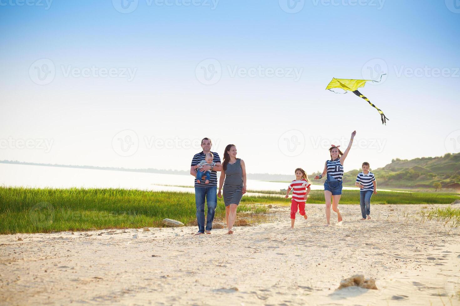 Happy young family with flying a kite on the beach photo