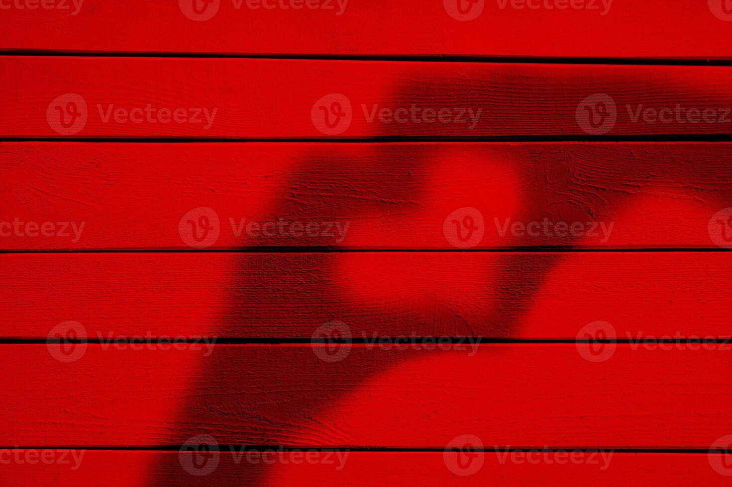 Two hands forming a heart shadow on red wood background photo
