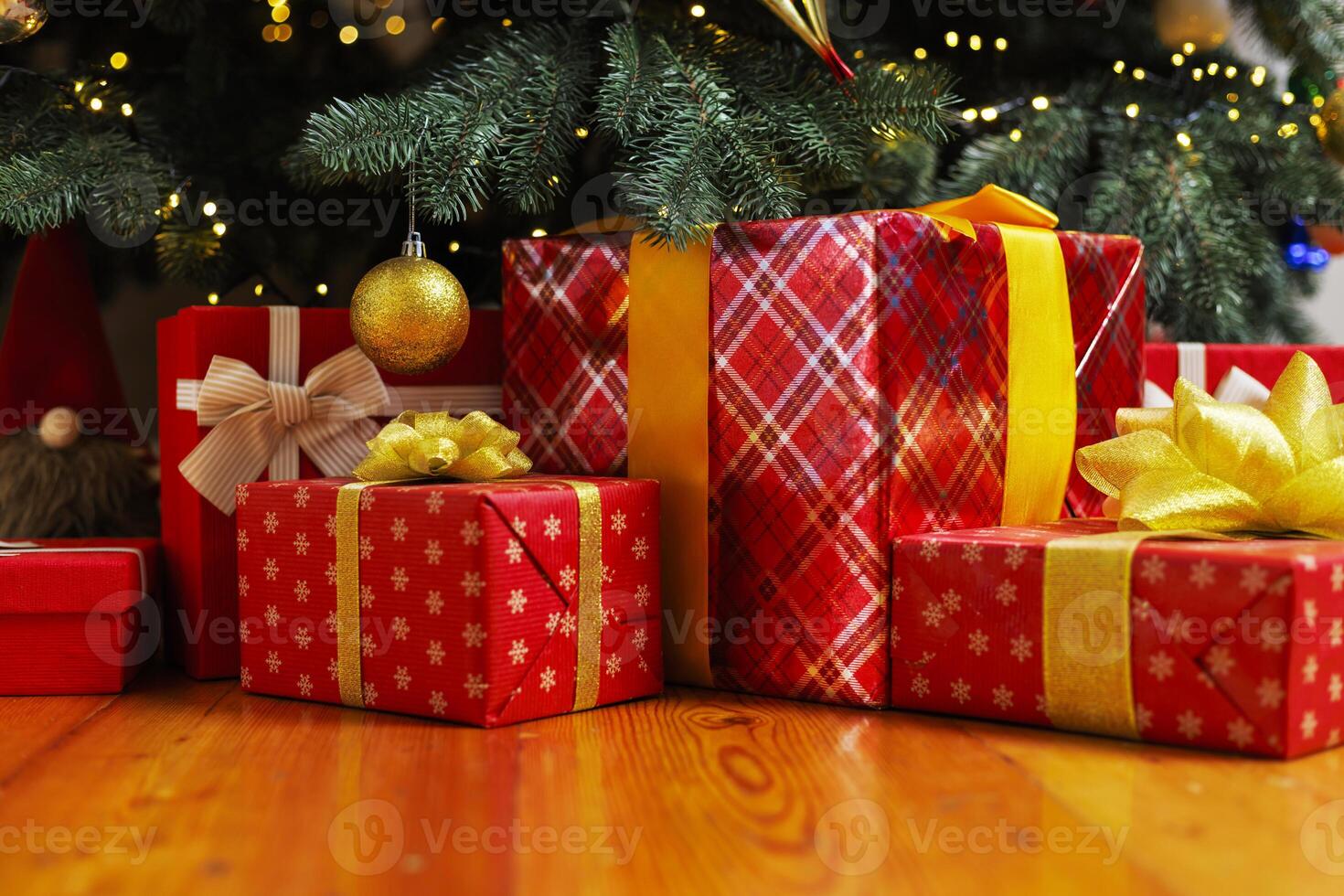 Pile of wrapped Christmas gifts under festive tree photo