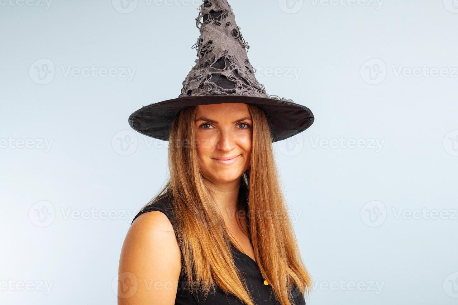Happy brunette woman in halloween witch costume with black hat photo