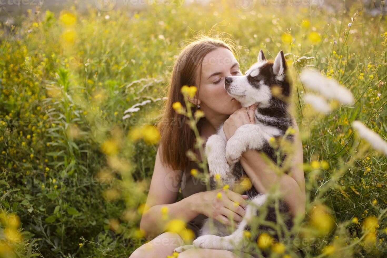 Beautiful young caucasian woman is playing with her puppy dog outdoor. photo