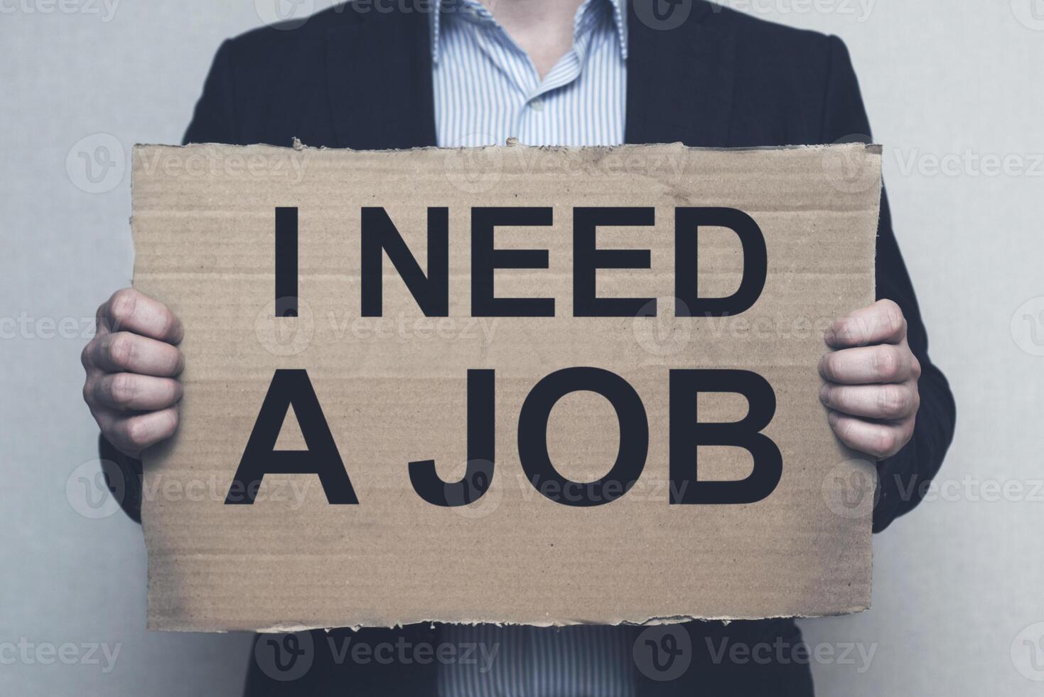 A man holding a cardboard with an inscription I NEED A JOB photo