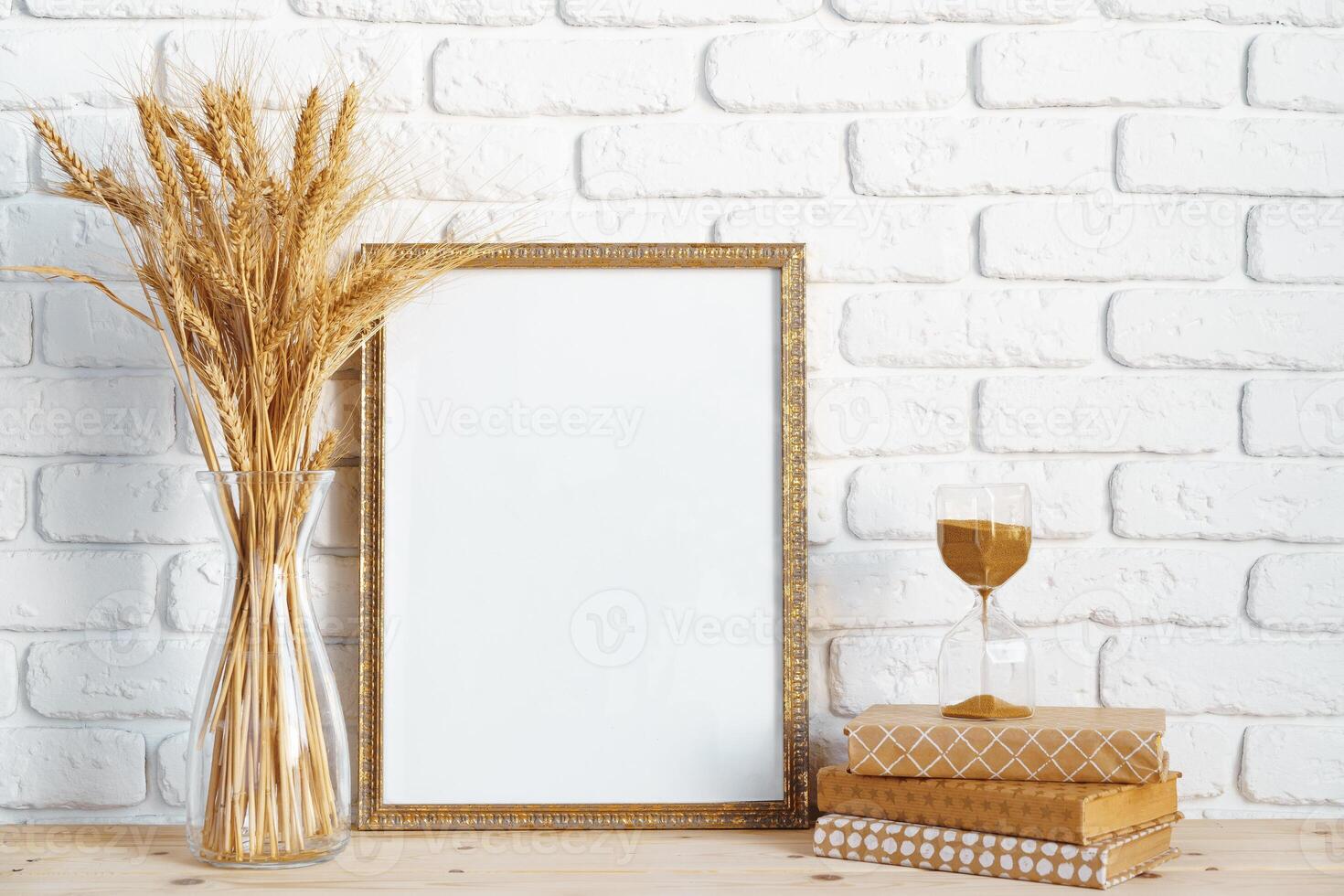 Vase with ears of wheat and photo frames against brick wall