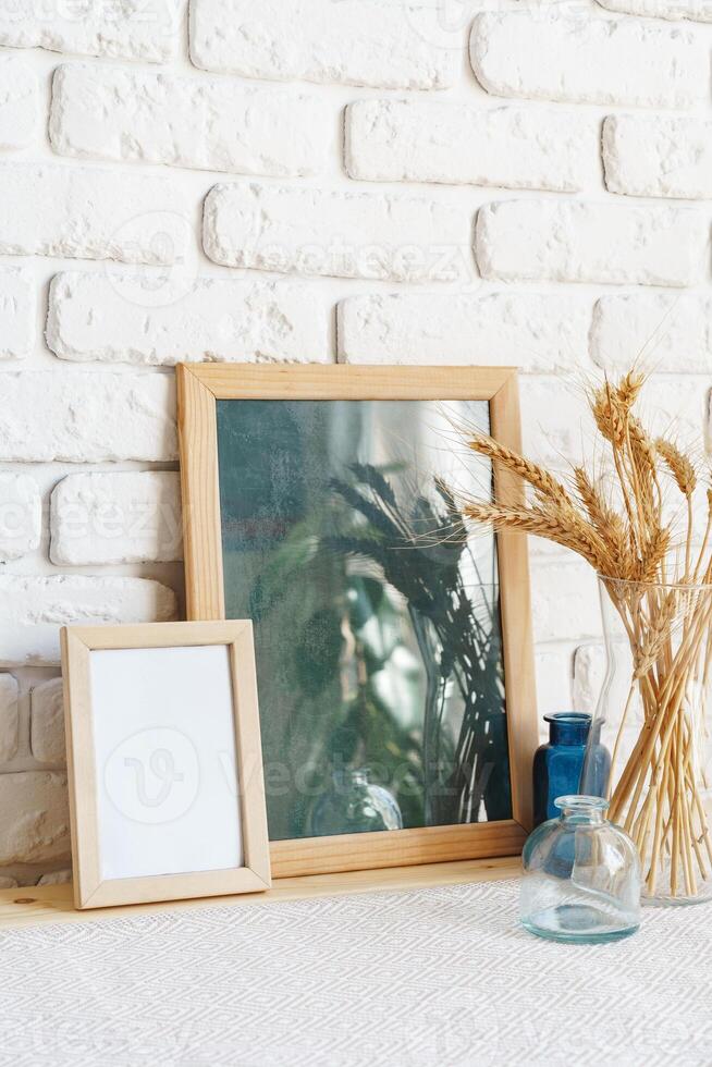 Mockup with a frame and dry flowers in a vase on a white table photo