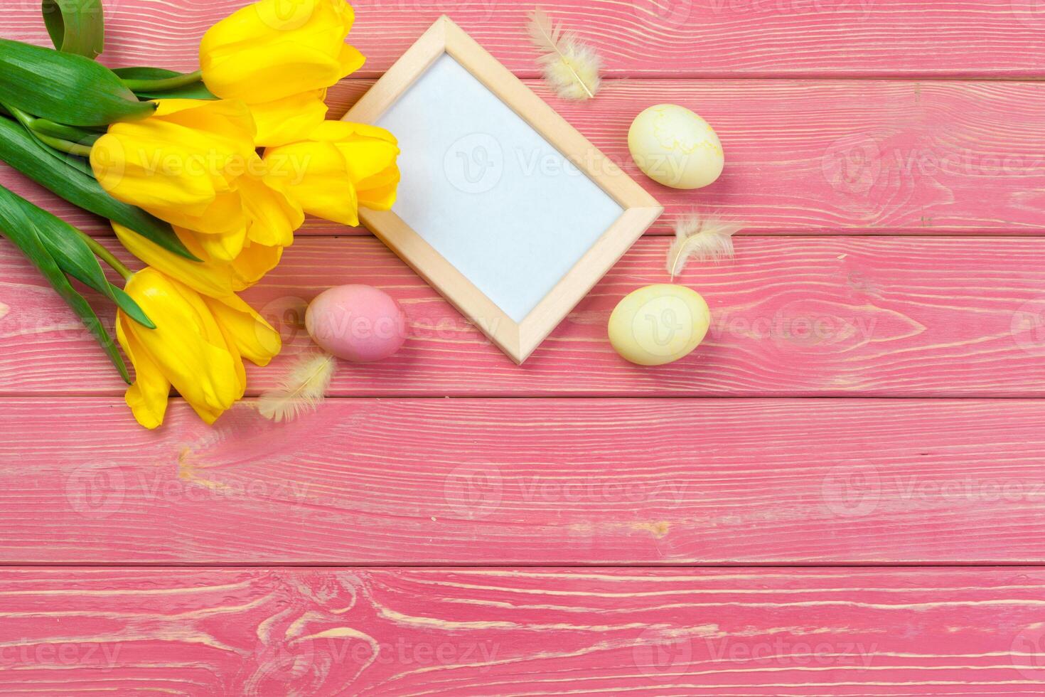Easter concept. Wooden frame with easter eggs and tulips on colorful background photo