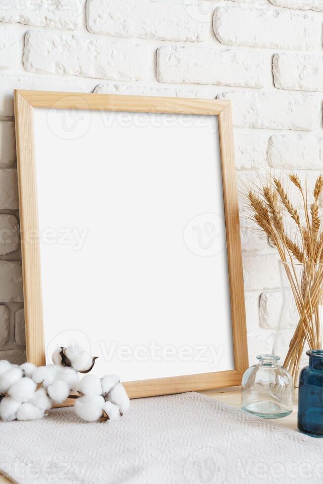 Vase with ears of wheat and photo frames against brick wall
