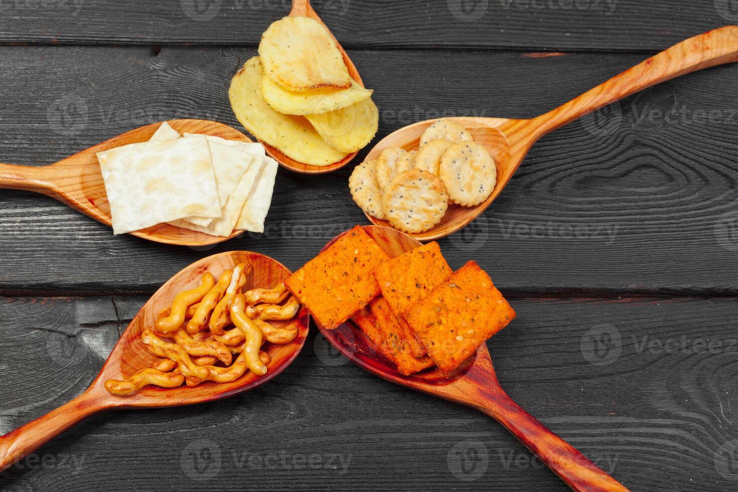 Mix of snacks . pretzels , crackers , chips and nachos on the table photo