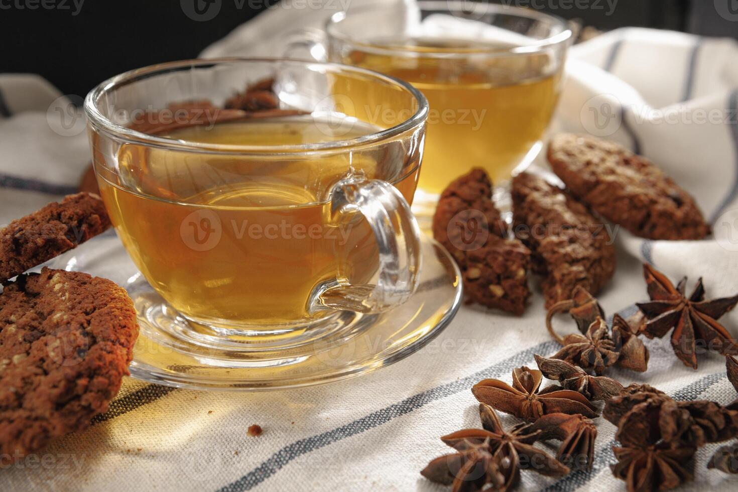 Two cups of herbal tea and cookies on kitchen cloth photo