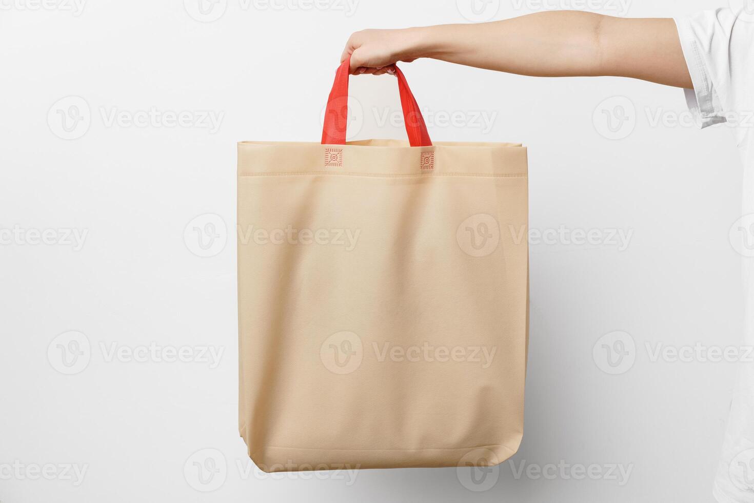 Female hand holding eco or reusable shopping bag against white background photo
