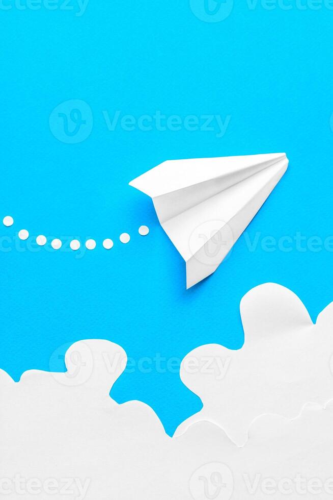 Flying paper plane in the clouds on a blue background. Concept of flight, travel, transfer photo