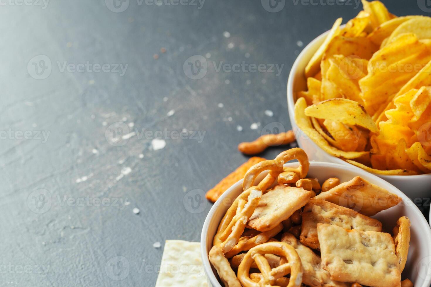 Beer snacks on stone table. Various crackers, potato chips. Top view photo