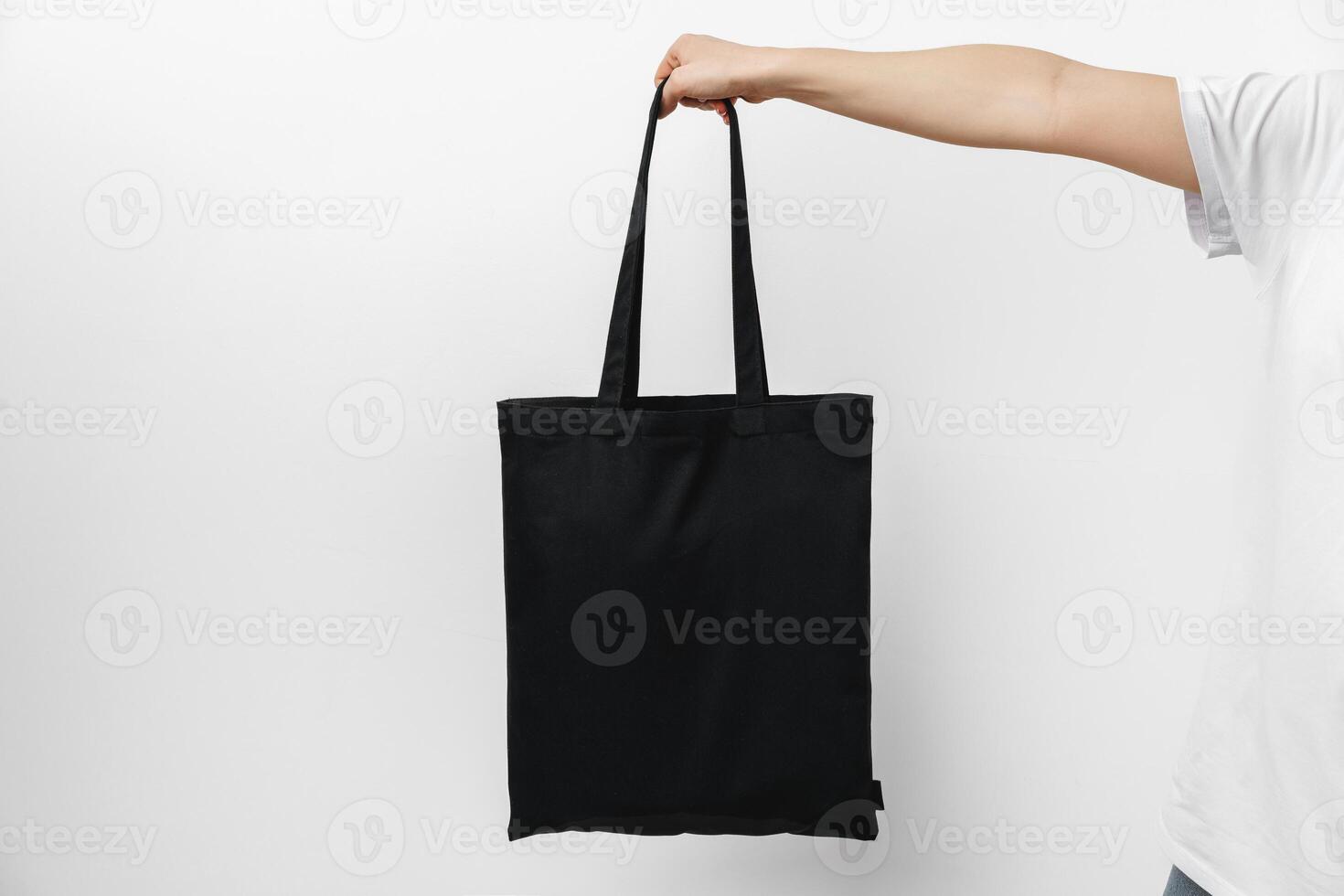 Female hand holding eco or reusable shopping bag against white background photo