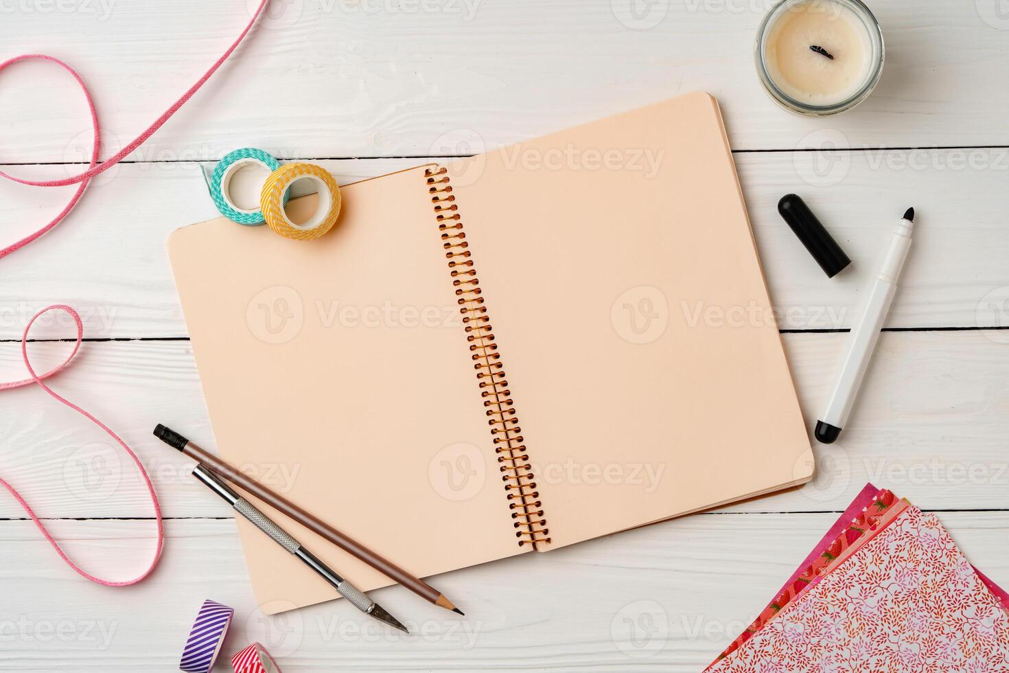 Creative workspace with open notebook, stationery, and decorative items on a wooden table photo