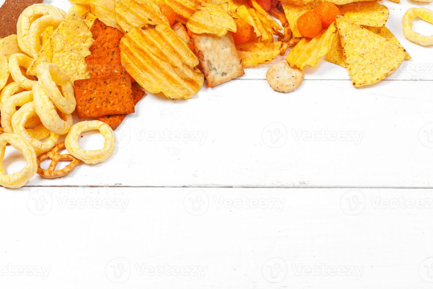 Mix of snacks . pretzels , crackers , chips and nachos on the table photo