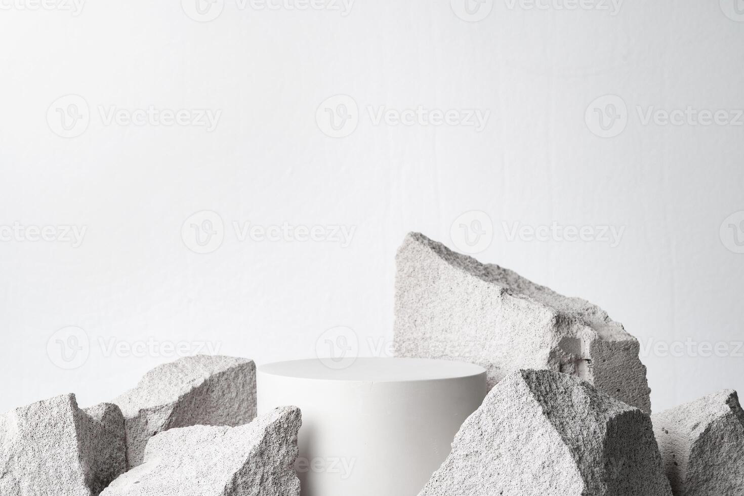 A minimalistic display featuring a smooth white cylinder surrounded by rough gray stone fragments photo