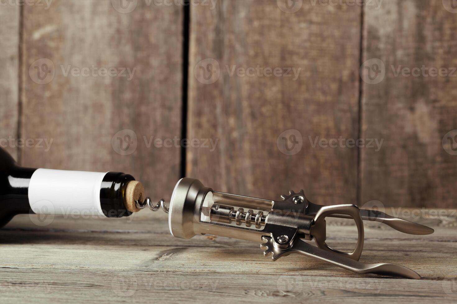 Bottle of wine with corkscrew on wooden background photo